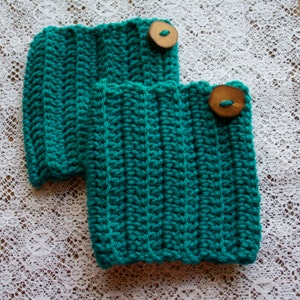 Puede incluir: Dos calentadores de piernas de color azul turquesa hechos a crochet con botones de madera.