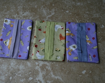May include: Three fabric tissue holders with a chicken and egg design. The holders are purple, green, and blue with a white and yellow chicken and egg pattern.