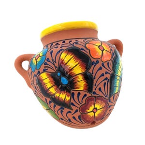 May include: Hand-painted terracotta wall planter with a yellow rim and two handles. The planter is decorated with colorful floral designs in shades of yellow, orange, blue, and red, set against a brown background.