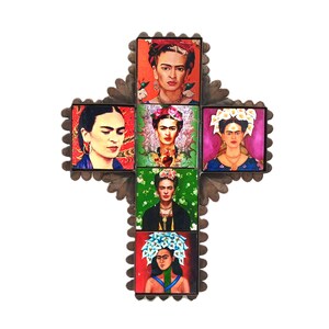 May include: A decorative cross featuring six portraits of Frida Kahlo. The portraits are set within a metal frame with a scalloped edge. Each portrait showcases Kahlo in various outfits and floral headpieces, with vibrant colors.