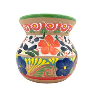 May include: A hand-painted ceramic vase with a wide, rounded body and a narrow neck. The vase features a vibrant floral design with red, orange, blue, and yellow flowers, green leaves, and a red and green rim. The background is a natural tan color.
