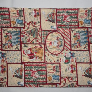 May include: A rectangular Christmas-themed drawstring bag. The bag features a repeating pattern of Santa Claus, Christmas trees, and gifts in red, green, and cream colors. The bag has a cream-colored drawstring.