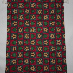 May include: A red drawstring bag with a Christmas tree and star pattern. The bag is made of fabric and has a white drawstring.