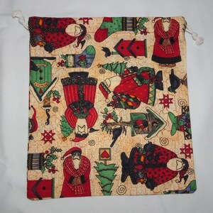 May include: A beige fabric drawstring bag with a Christmas theme. The bag is covered in a repeating pattern of Santa Claus figures, birds, houses, and Christmas trees. The pattern is in shades of red, green, black, and white.