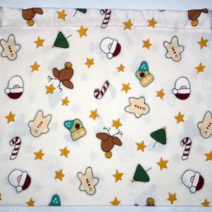 May include: A white cotton drawstring bag with a Christmas-themed print. The print features stars, candy canes, reindeer, Christmas trees, and gingerbread men.