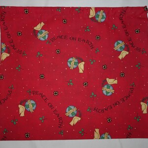 May include: Red fabric drawstring bag with a white drawstring. The bag is covered in a repeating pattern of white doves holding a globe with the text "Peace on Earth" around it. The background is a red color with white dots.