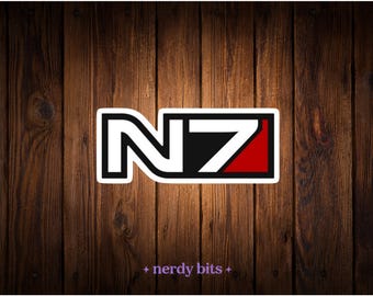 May include: A rectangular sticker featuring the N7 logo with a white letter N and the number 7, which has a red triangular accent on the bottom right corner. The design is outlined in white and includes the text nerdy bits at the bottom.
