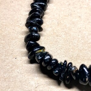 May include: Black gemstone bracelet with small, irregularly shaped beads.