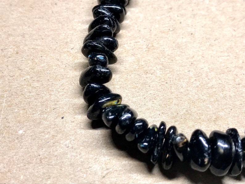 May include: Black gemstone bracelet with small, irregularly shaped beads.