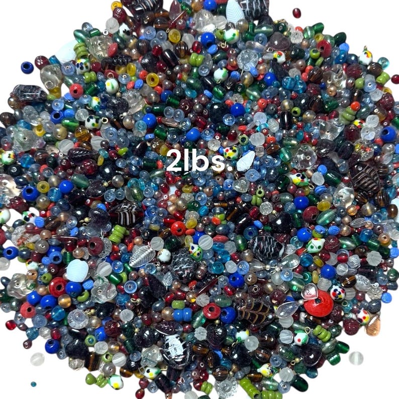 May include: A large pile of colorful beads in various shapes and sizes. The beads are a mix of colors including red, blue, green, and clear. The text "2lbs." is visible in white. These beads are ideal for jewelry making and crafts.