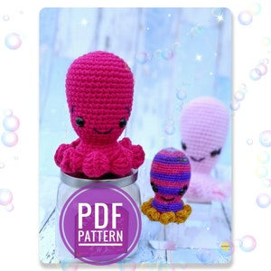 May include: Three crocheted octopus amigurumi toys in pink, purple and white. The pink octopus is sitting on a glass jar with a label that says "PDF PATTERN".