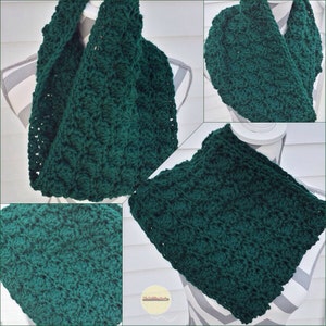 May include: A dark green, handmade crochet infinity scarf. The scarf is displayed on a mannequin, showcasing its textured stitch pattern. The close-up reveals the detailed craftsmanship of the yarn. This cozy accessory is perfect for adding warmth and style.