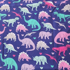 May include: A dark blue fabric featuring a repeating pattern of various dinosaurs in shades of pink, light green, and light gray, interspersed with small pink and light green hearts throughout the design, creating a dense and colorful dinosaur print.