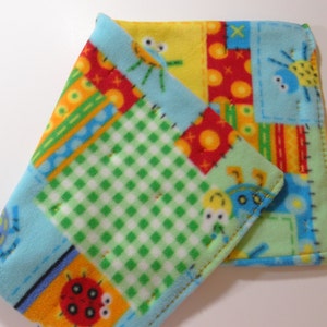 May include: A patchwork baby blanket with a blue, green, yellow, and red color scheme. The blanket features a variety of cartoon animals, including a ladybug, a spider, and a bee.