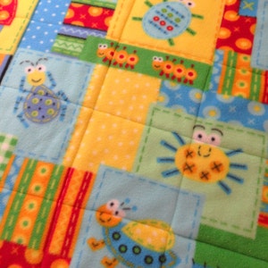 May include: A colorful patchwork fabric with a variety of bug and insect designs. The fabric features a blue, yellow, green, and red color scheme. The fabric is perfect for quilting, sewing, and crafting projects.