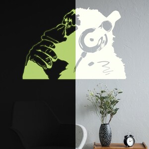 May include: Glow-in-the-dark wall decal of a person wearing headphones. The decal is split in half, with the left side glowing green and the right side white.