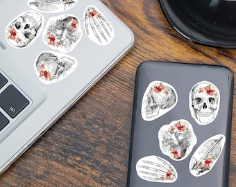 May include: A set of 8 black and white anatomical illustrations of skulls and bones with floral accents. The stickers are on a laptop and a phone.