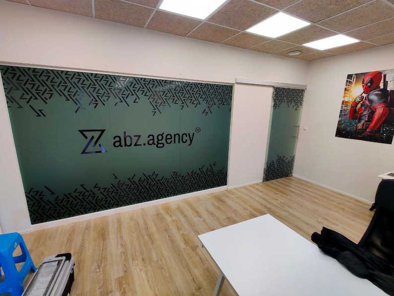 Puede incluir: Un espacio de oficina moderno con una pared de vidrio esmerilado que presenta un patr&oacute;n geom&eacute;trico en blanco y negro y el logotipo "abz.agency".