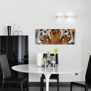 May include: Close-up of a tiger's face with snow on its fur. The tiger's eyes are focused on the viewer. The image is printed on a canvas and framed.