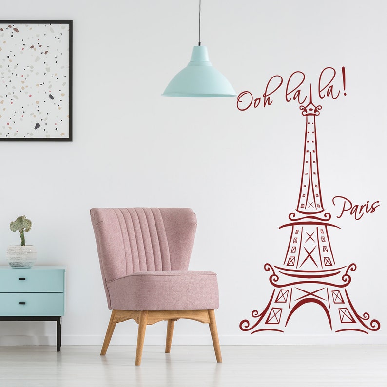 May include: A pink armchair with wooden legs sits in front of a white wall with a red Eiffel Tower design and the text "Ooh la la! Paris".