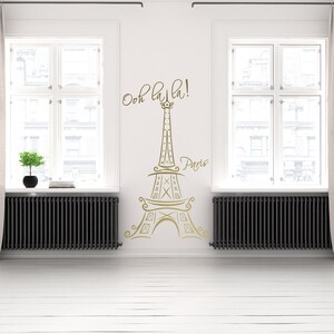 May include: A gold Eiffel Tower wall decal with the text "Ooh la la! Paris" on a white wall.