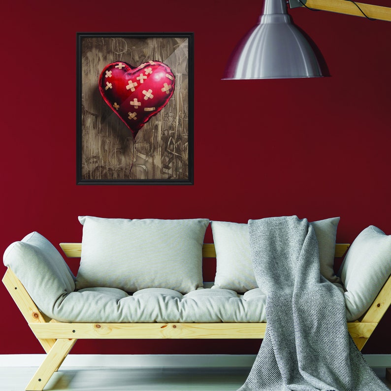 May include: A framed print of a red heart-shaped balloon with multiple band-aid patches on it. The balloon is floating against a brown, textured background.