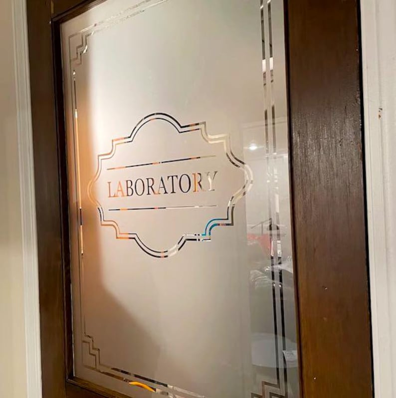 Puede incluir: Una puerta de vidrio esmerilado con un marco decorativo y la palabra "LABORATORY" impresa en letras negras.
