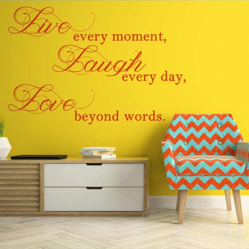 May include: A yellow wall with a red cursive quote that reads "Live every moment, Laugh every day, Love beyond words." A teal and orange chevron patterned armchair sits in front of the wall.