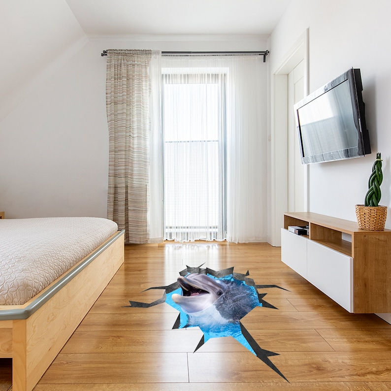 May include: A 3D floor sticker of a dolphin jumping out of a cracked floor. The dolphin is gray and white with a blue background. The sticker is perfect for adding a fun and unique touch to any room.