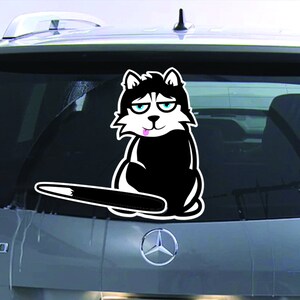 May include: A black and white cartoon husky dog sticker with a pink tongue sticking out. The dog is sitting on its hind legs with its tail sticking out behind it. The sticker is on the back window of a car.