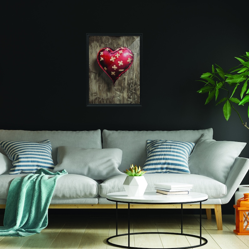 May include: A red heart-shaped object with a distressed texture, covered in beige bandages, is displayed in a black frame against a dark background.