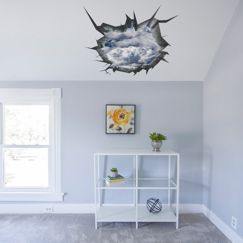 Puede incluir: Una estanter&iacute;a blanca con tres estantes, una tapa de vidrio y un marco de metal. La estanter&iacute;a est&aacute; decorada con una pintura floral amarilla, una peque&ntilde;a planta en maceta y una esfera decorativa. La estanter&iacute;a est&aacute; delante de una pared gris claro con una pegatina de techo decorativa de una pared agrietada que revela un cielo azul con nubes blancas.