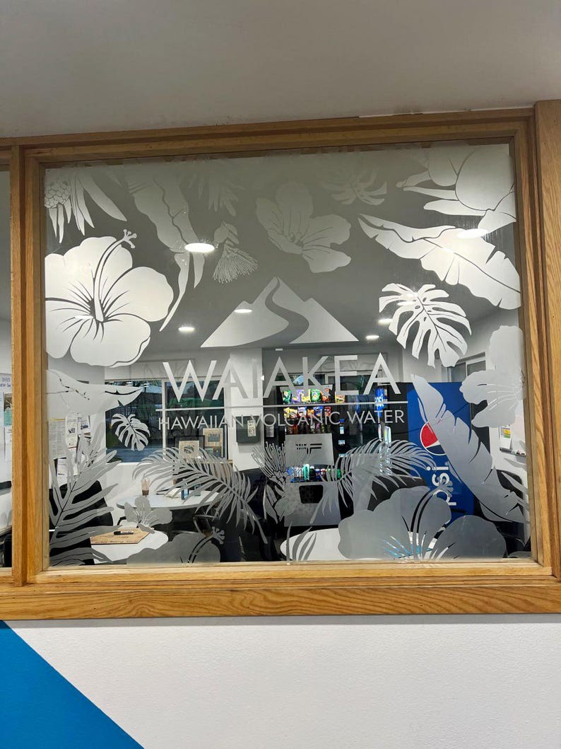 Puede incluir: Una ventana de vidrio esmerilado con un dise&ntilde;o blanco de plantas y flores tropicales. El texto "Waiakeal Hawaiian Volcanic Water" es visible en la parte inferior de la ventana.