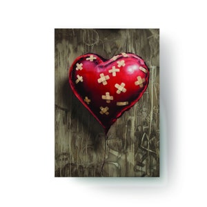 May include: A red heart-shaped balloon with multiple beige band-aid patches on it. The balloon is deflated and hanging from a string. The background is a textured, brown surface.
