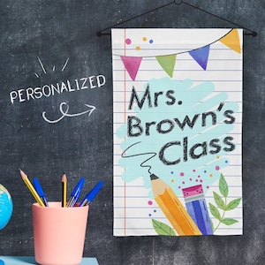 May include: A white classroom banner with blue lines and a blue and yellow pencil design. The banner says "Mrs. Brown's Class" in black text.