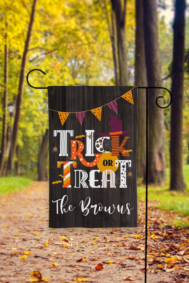 May include: A black and white Halloween garden flag with the words "Trick or Treat" in colorful letters. The flag also has a witch's hat, bats, and spiderwebs. The text "The Browns" is at the bottom of the flag.