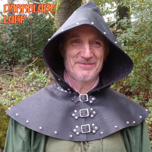 May include: A black leather hooded cowl with silver studs and buckles. The cowl has a pointed hood and a wide collar.
