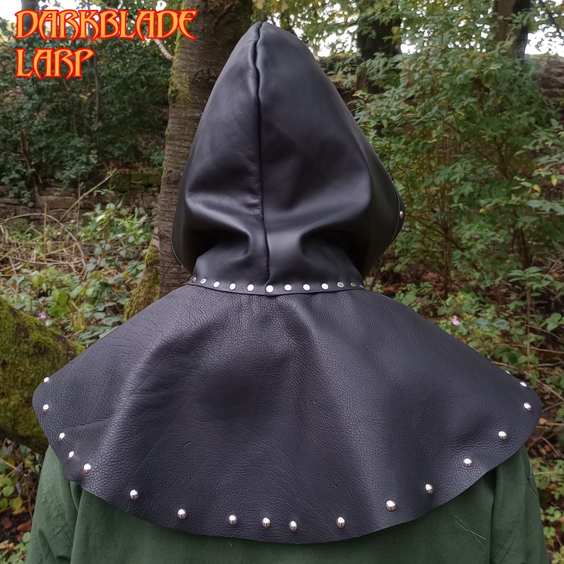 May include: Black leather hooded cowl with silver studs. The cowl has a pointed hood and a wide collar.