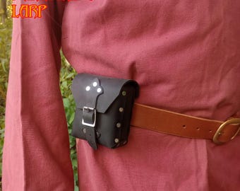 Puede incluir: Una bolsa de cuero negro con una hebilla plateada y detalles metálicos. La bolsa está unida a un cinturón de cuero marrón.