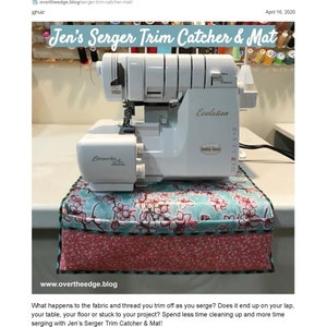 Könnte beinhalten: Eine weiße Overlock-Nähmaschine mit der Bezeichnung "Evolution" steht auf einem Trimmfänger und einer Matte mit floralem Muster. Die Matte hat ein rosa- und türkisfarbenes Blumendesign. Der Text "Jen's Serger Trim Catcher & Mat" ist sichtbar.