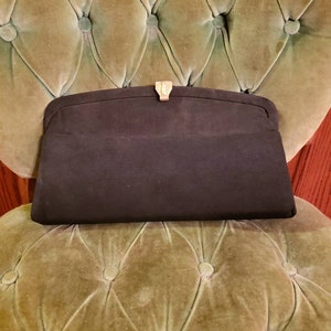 May include: A black fabric clutch purse with a gold clasp.