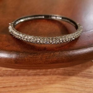 May include: A silver bangle bracelet with a row of clear rhinestones.