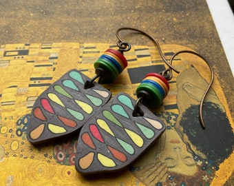 May include: A pair of handmade earrings with a black clay base and colorful teardrop shapes. The earrings are attached to a brown wire with a multi-colored bead.