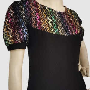 May include: A black dress with a rainbow sequin neckline and short sleeves.