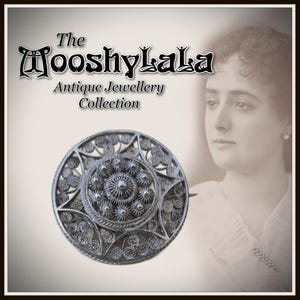 May include: An antique silver-toned brooch with an intricate, circular filigree design. The brooch features a central starburst pattern surrounded by floral and geometric details. The text reads "The Mooshylala Antique Jewellery Collection."