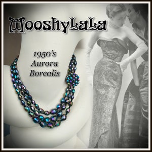 May include: A three-strand necklace made of iridescent blue and black faceted glass beads. The necklace has a large, round, iridescent blue and black brooch in the centre. The text "1950's Aurora Borealis" is written on the image.