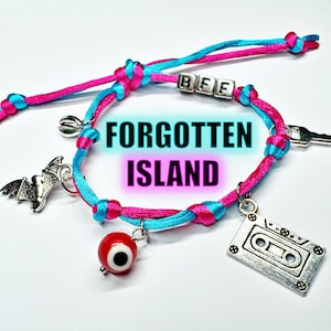 Könnte beinhalten: Ein Armband aus geflochtener, leuchtend pinker und cyanfarbener Kordel mit silberfarbenen Anhängern wie einer Fledermaus, einem Schlüssel, einer Kassette und einer Muschel, sowie einer roten Auge-Perle und Silberwürfeln mit der Aufschrift BFF.
