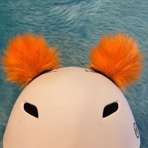 Bear Ears, not Pom poms that sticks on (Your Helmet) comes in different colors Look at my site. Helmet fun safety Be Seen and safe read,