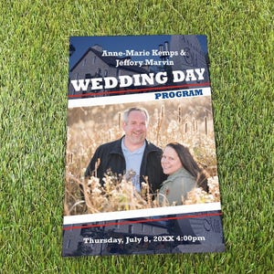 May include: A rectangular wedding day program featuring a photograph of a couple in a field. The text reads: Anne-Marie Kemps & Jeffory Marvin, WEDDING DAY PROGRAM, and Thursday, July 8, 20XX 4:00pm. The design includes blue and red horizontal lines.