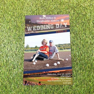 May include: A rectangular wedding program featuring a photo of two people in baseball jerseys on a field with bats and balls. The text reads Rob Miller & Stephanie Alders, WEDDING DAY PROGRAM, Saturday, May 26, 20XX, AT&T Park, 24 Willie Mays Plaza, San Francisco, CA 94107, 2:00 pm.